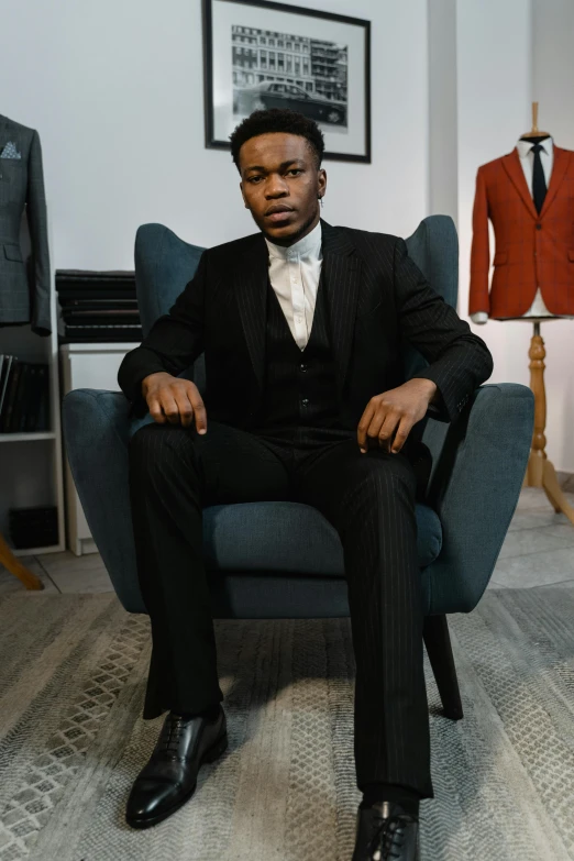 a man in a suit sitting in a chair, inspired by Barthélemy Menn, pexels contest winner, black teenage boy, three piece suit, tuxedo, old wool suit