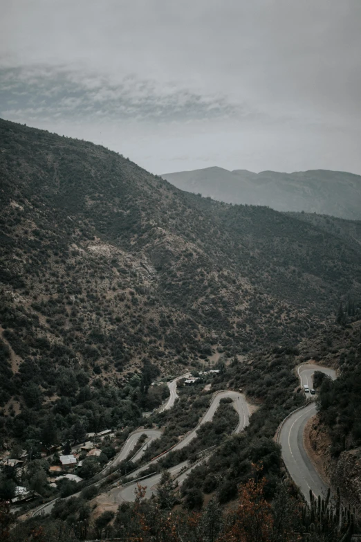 a winding road in the mountains on a cloudy day, a picture, unsplash contest winner, cyprus, curls, grey, multiple stories