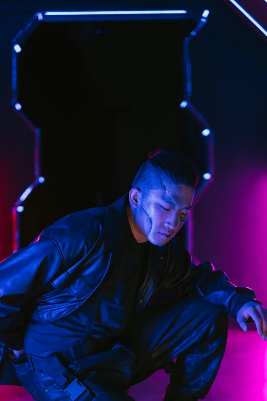 a man kneeling down in front of a neon light, inspired by Zhu Da, looking away from camera, sitting, actor, reflecting light in a nightclub