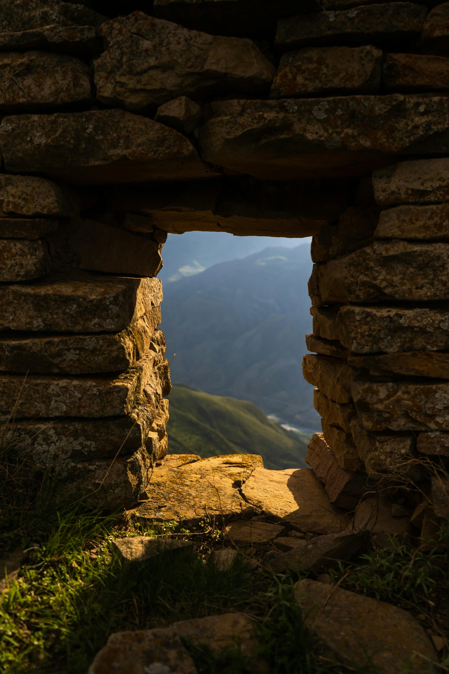 a window in a stone wall with mountains in the background, by Peter Churcher, unsplash contest winner, peru, back light, hobbit hole, ruined temple