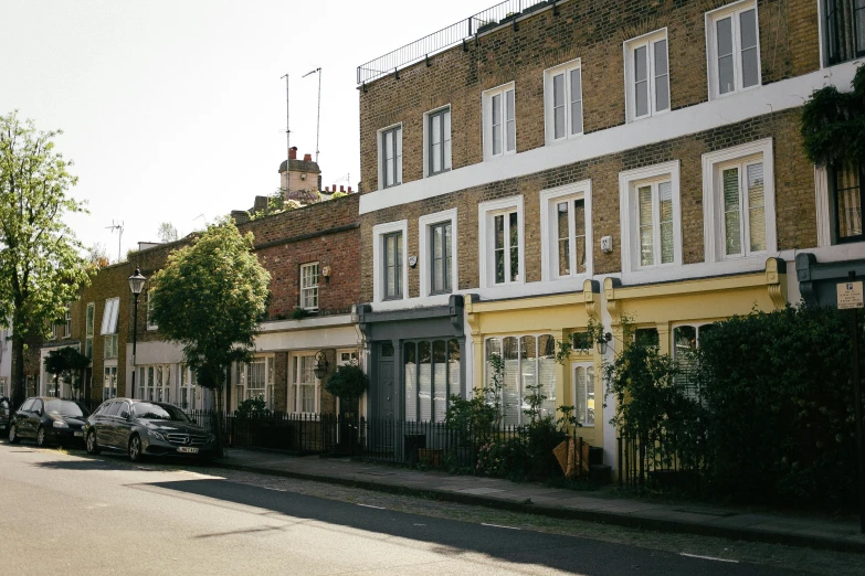 a couple of cars parked on the side of a road, by Rachel Reckitt, unsplash, modernism, houses and buildings, victorian london, ignant, tall terrace