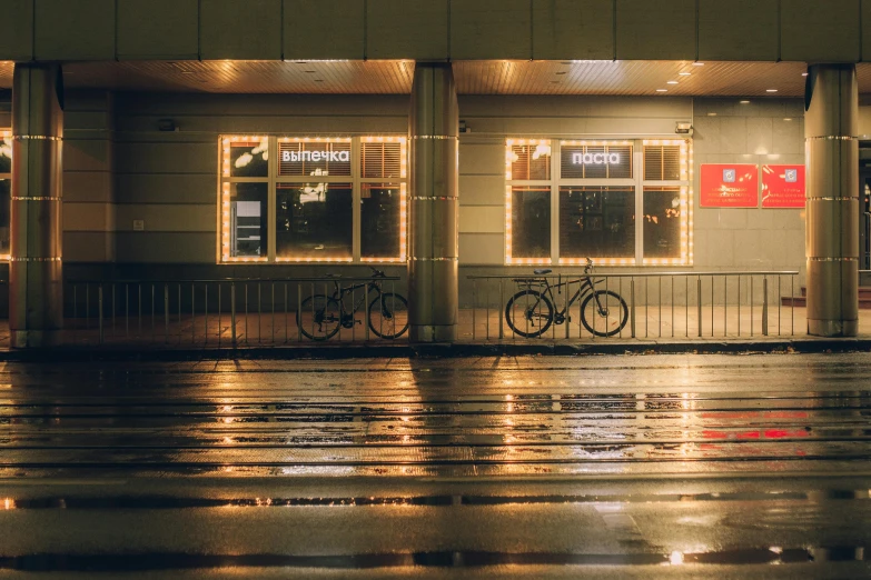 a bicycle parked in front of a building at night, inspired by Elsa Bleda, unsplash contest winner, realism, bus stop on a rainy day, espoo, lamps on ground, in front of ramen shop