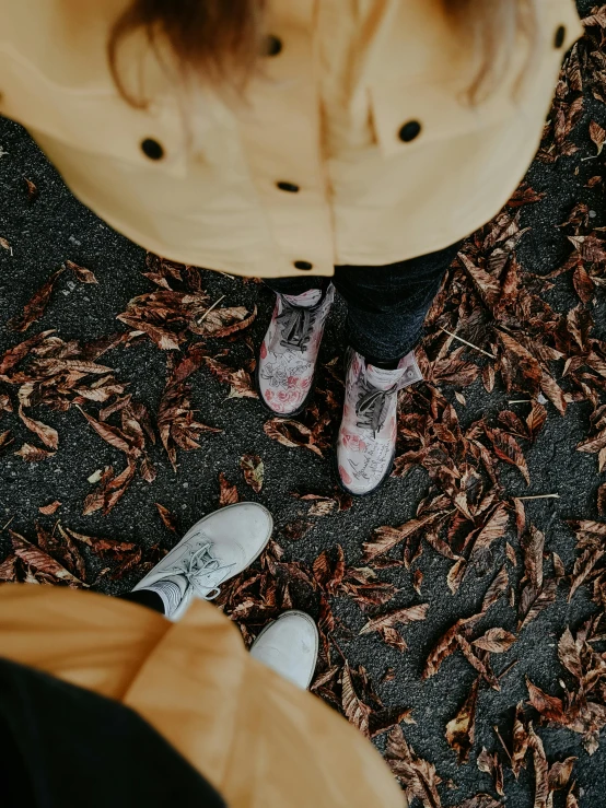 a couple of people standing next to each other, by Lucia Peka, trending on pexels, autumn leaves on the ground, thumbnail, background image, after rain and no girls