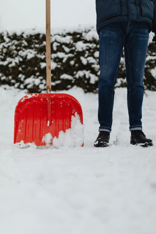 a person standing in the snow with a snow shovel, only red colour, rectangle, at home, full width