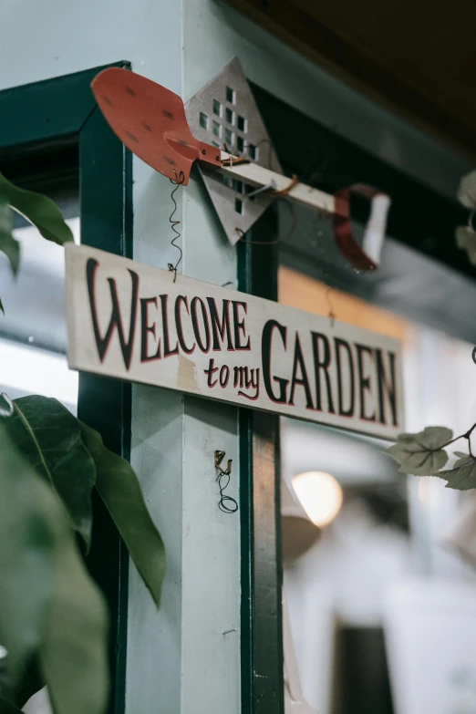 a welcome sign hanging on the side of a building, by Sam Dillemans, trending on unsplash, backyard garden, misty garden, indoor picture, half image