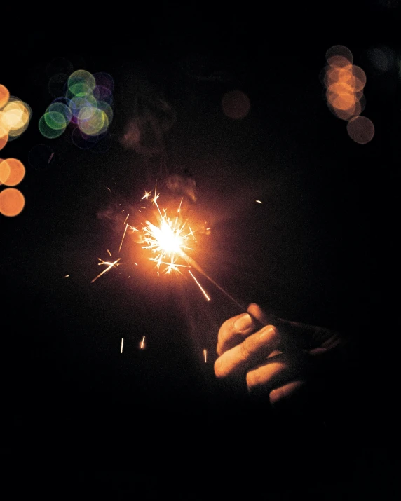 a person holding a sparkler in their hand, an album cover, by Niko Henrichon, unsplash, multiple stories, lgbtq, holiday season, grainy photo