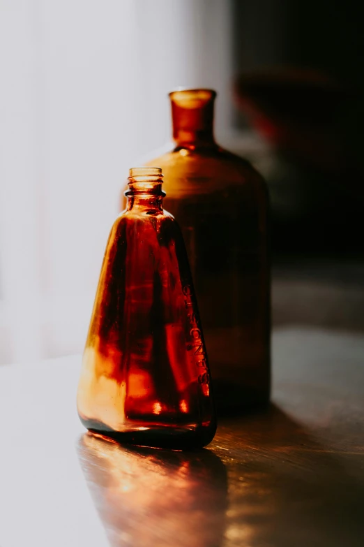 a brown glass bottle sitting on top of a wooden table, a still life, unsplash, amber glow, chemicals, profile pic, worn