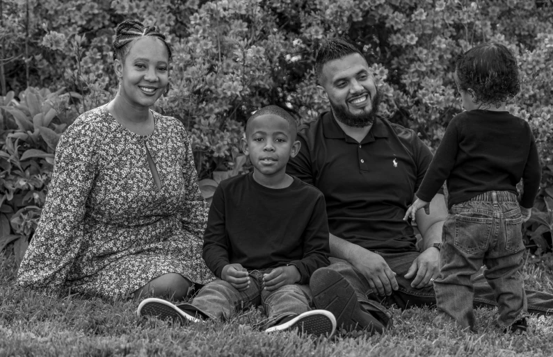 a black and white photo of a family sitting in the grass, a black and white photo, riyahd cassiem, joel torres, husband wife and son, jemal shabazz