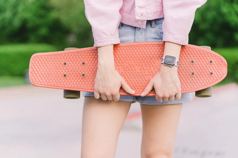 a close up of a person holding a skateboard, trending on pexels, wearing orange sundress, coral red, wearing a watch, wearing crop top and miniskirt