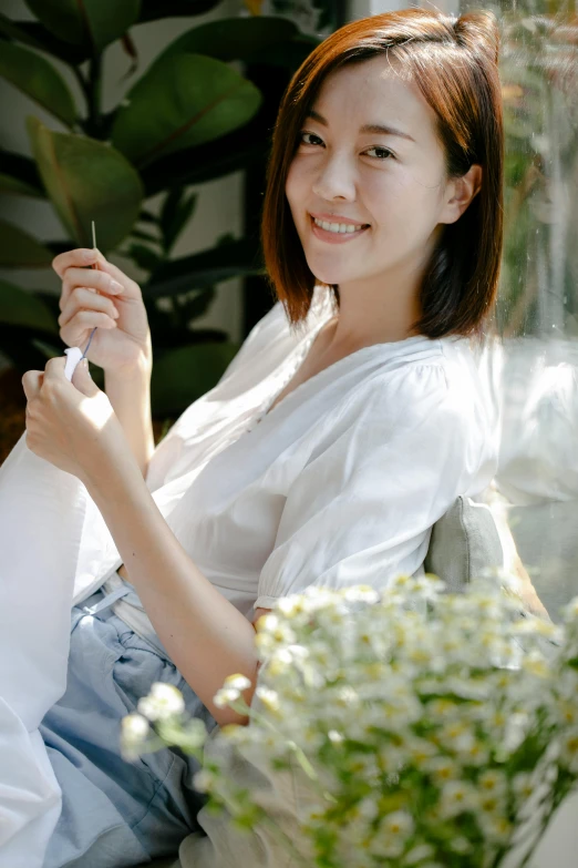 a woman sitting on a chair holding a cell phone, by Tan Ting-pho, pexels contest winner, wearing white v - neck top, with a garden, japanese collection product, made of lab tissue