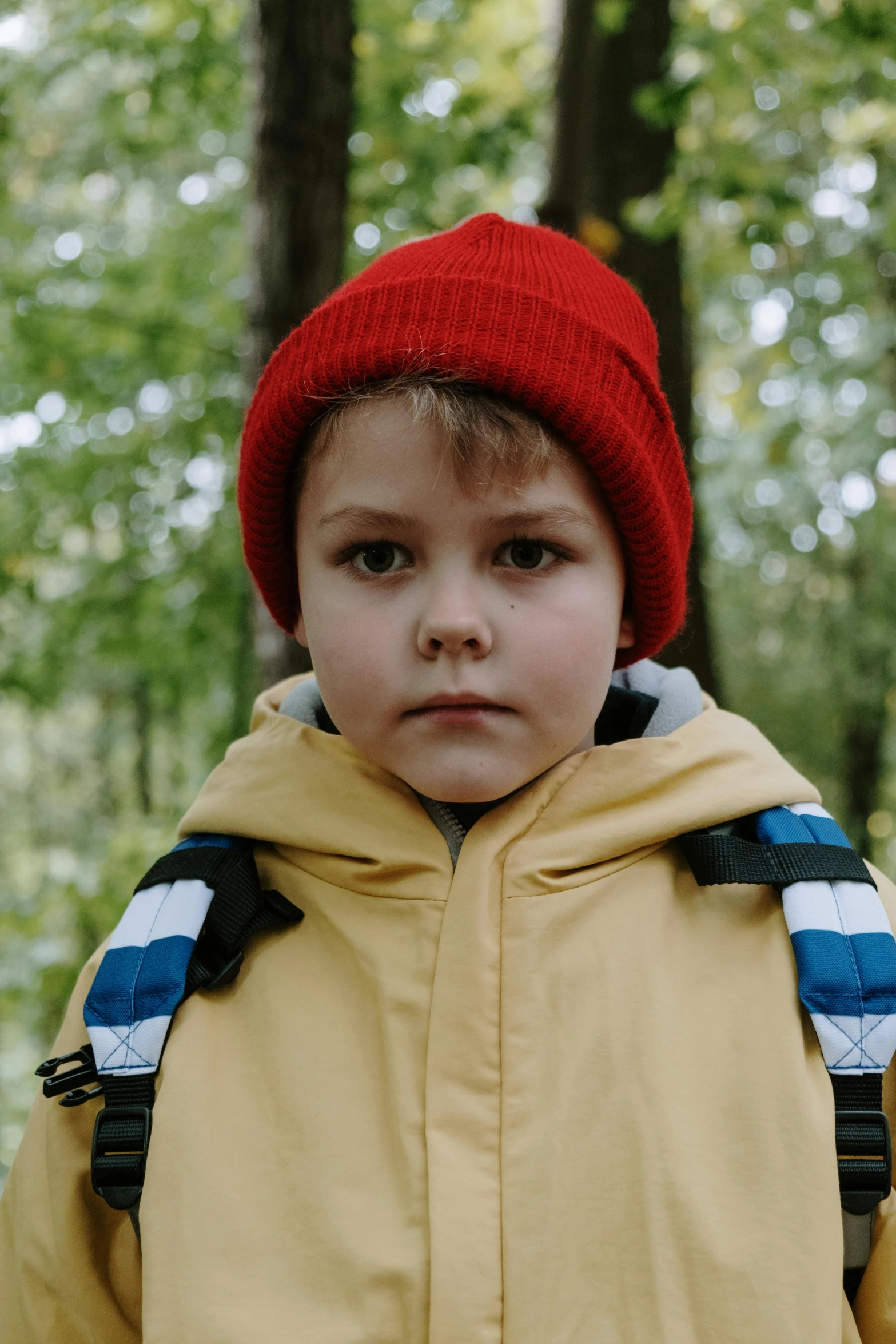 a young boy in a yellow jacket and a red hat, a picture, trending on pexels, movie still 8 k, forrest, very big eyes, hiking clothes