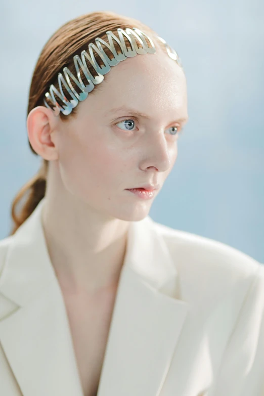 a woman wearing a white jacket and a silver headband, inspired by Maud Naftel, trending on reddit, surrealism, official jil sander editorial, pale blue, close - up studio photo, 2022 photograph