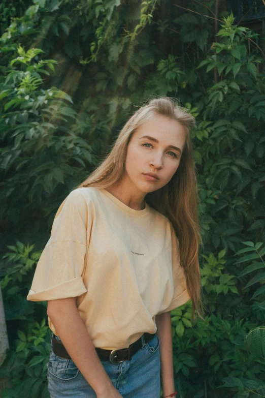 a young woman standing in front of a bush, trending on pexels, portrait of kim petras, wear's beige shirt, alina ivanchenko, 15081959 21121991 01012000 4k