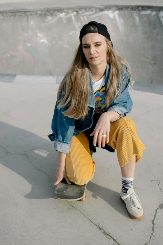 a girl sitting on a skateboard at a skate park, by Sara Saftleven, yellow cap, brit marling style 3/4, high-quality photo, promotional image