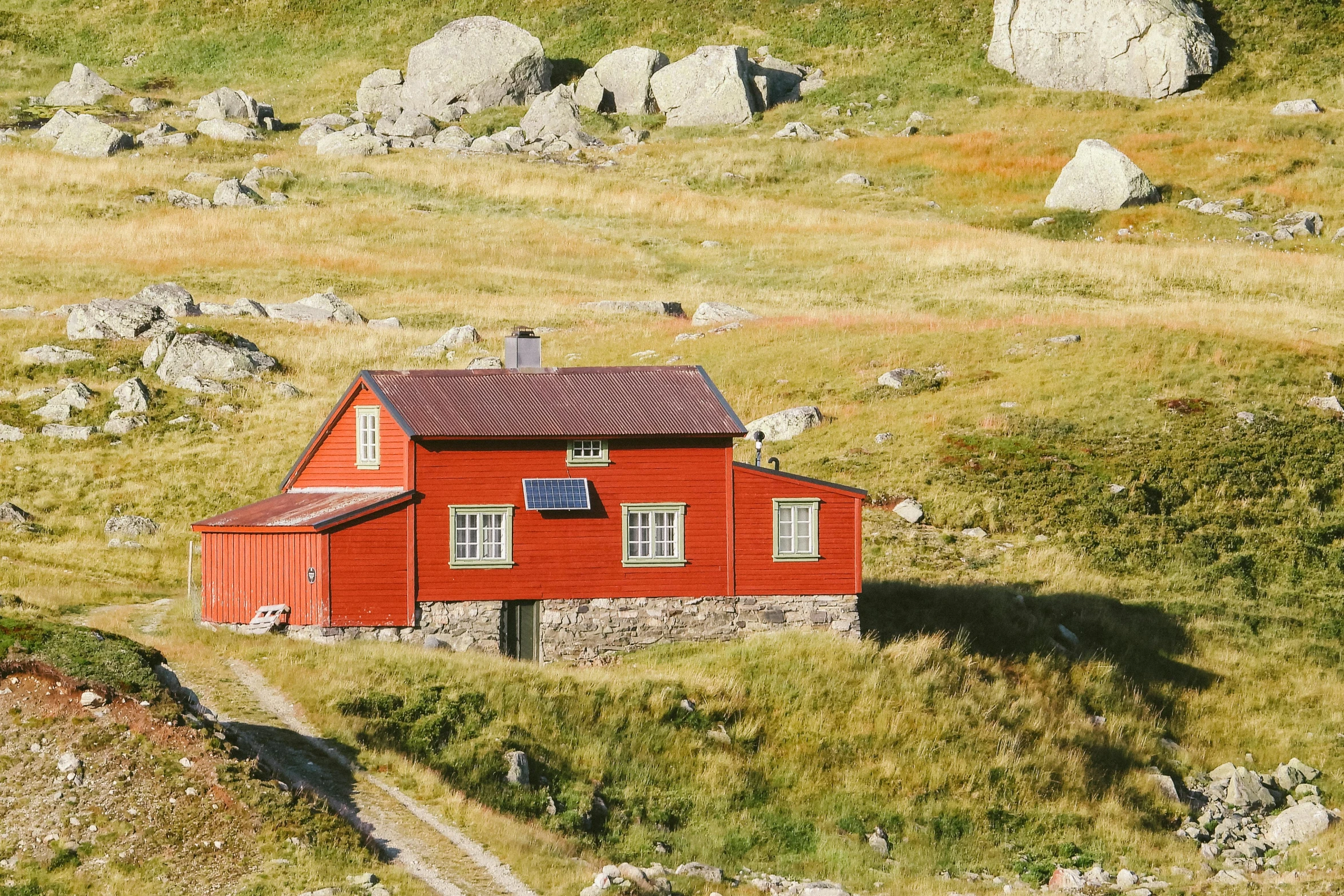 a red house sitting on top of a lush green hillside, by Jørgen Roed, interior of a mountain hut, profile image, golden hour photo, top - down photo