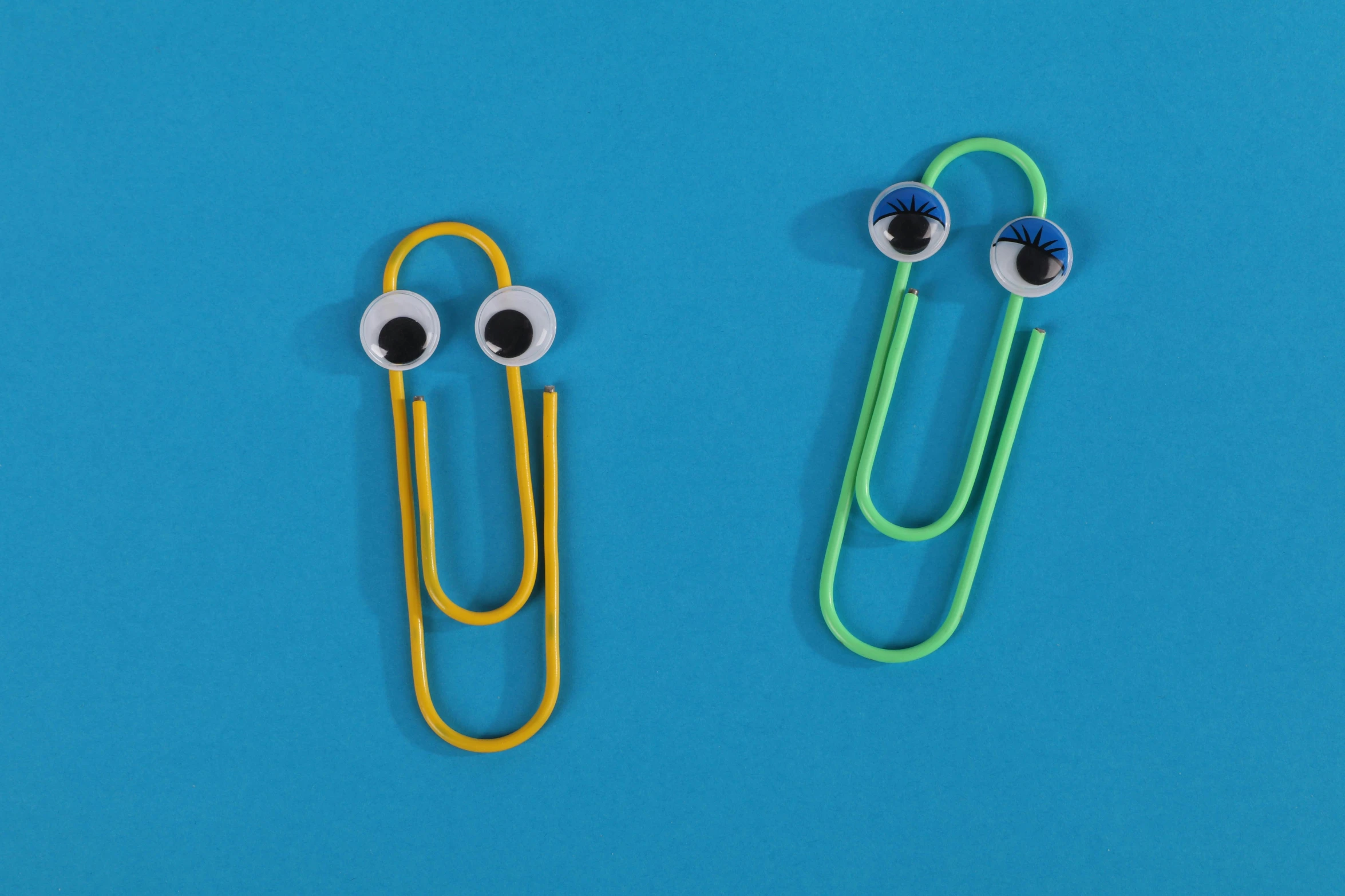 two paper clips with googly eyes on a blue background, pexels, teacher, slimy, piercing, modeled