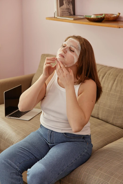 a woman sitting on a couch with a face mask on, happening, deformed face, candy treatments, pregnancy, scratches on photo