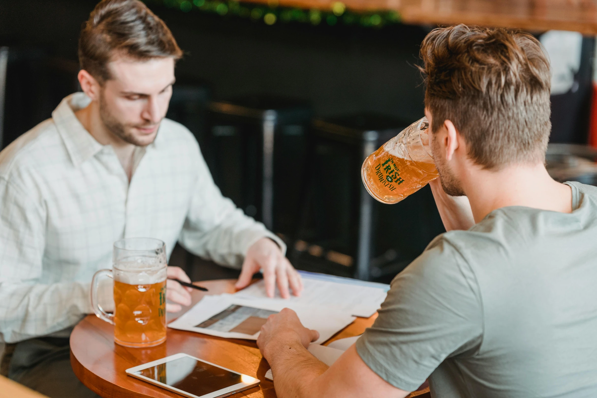 two men sitting at a table drinking beer, pexels contest winner, 9 9 designs, papers on table, aussie baristas, over it's head