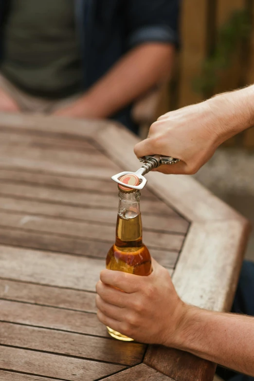 a close up of a person holding a bottle of beer, holding a crowbar, al fresco, sitting down, open top