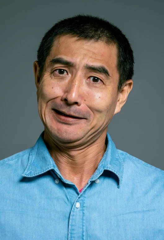 a man in a blue shirt posing for a picture, shin hanga, skeptical expression, on a gray background, kevin hou, middle aged man