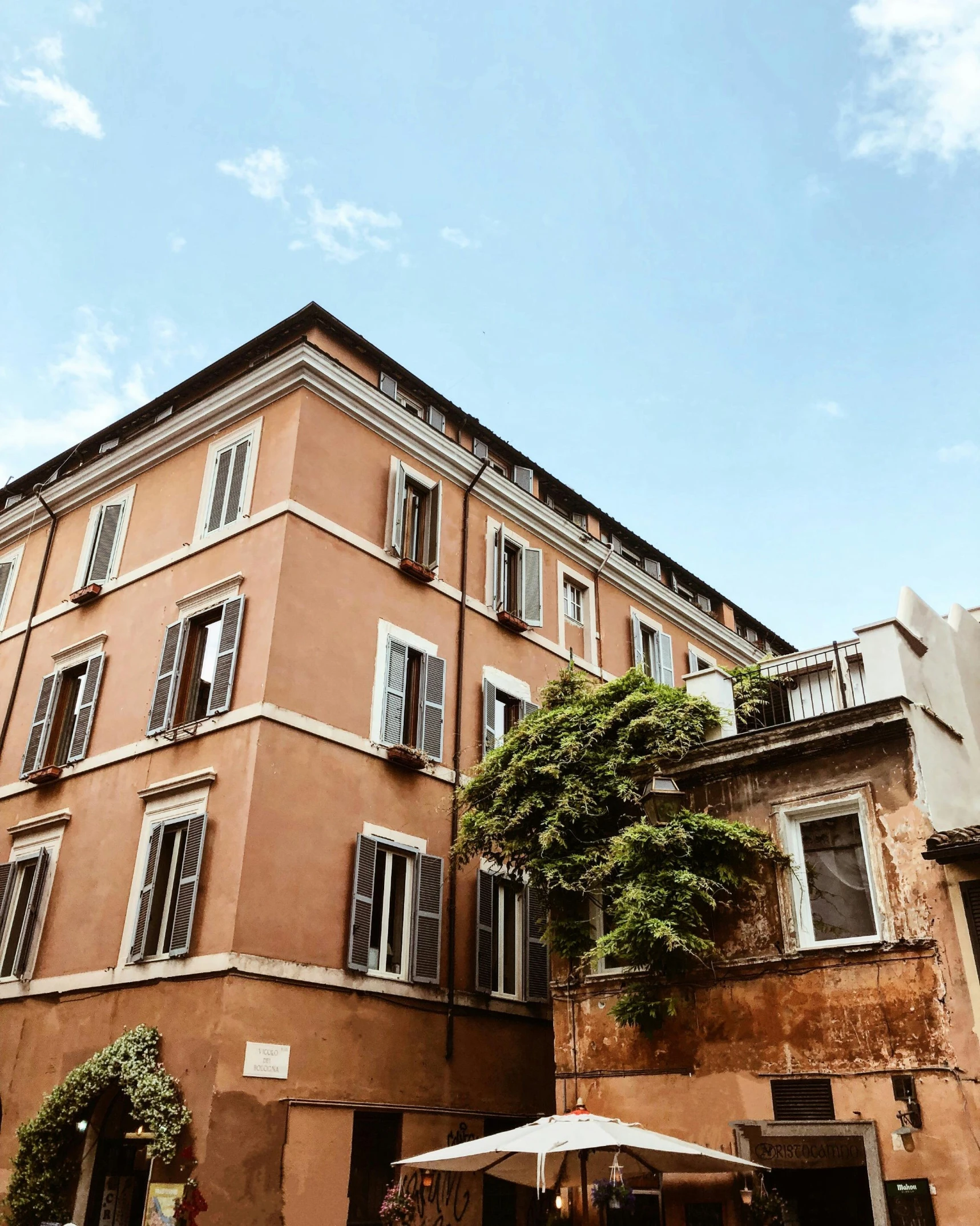 a tall building sitting on the side of a street, inspired by Michelangelo Buonarotti, pexels contest winner, neoclassicism, roof with vegetation, lgbtq, profile image, terracotta