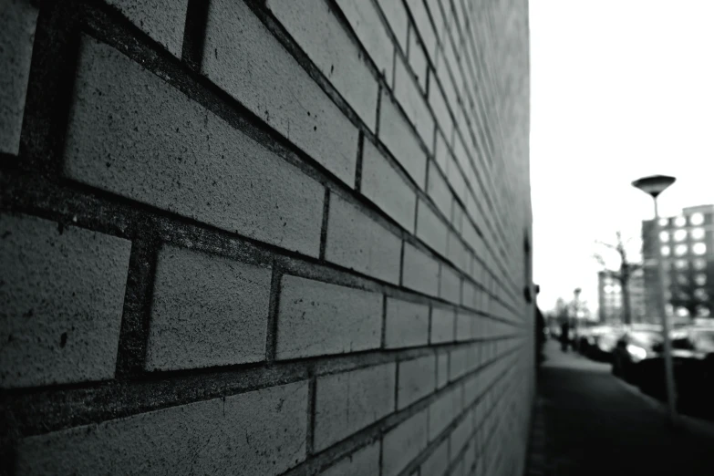 a black and white photo of a brick wall, by Pamphilus, angled shot, distant - mid - shot, focused photo, made of cement