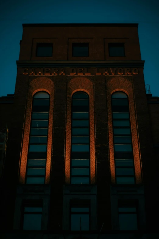 a tall brick building lit up at night, by Giuseppe Camuncoli, the golden hour, low quality photo, dramatic lighting - n 9, factory