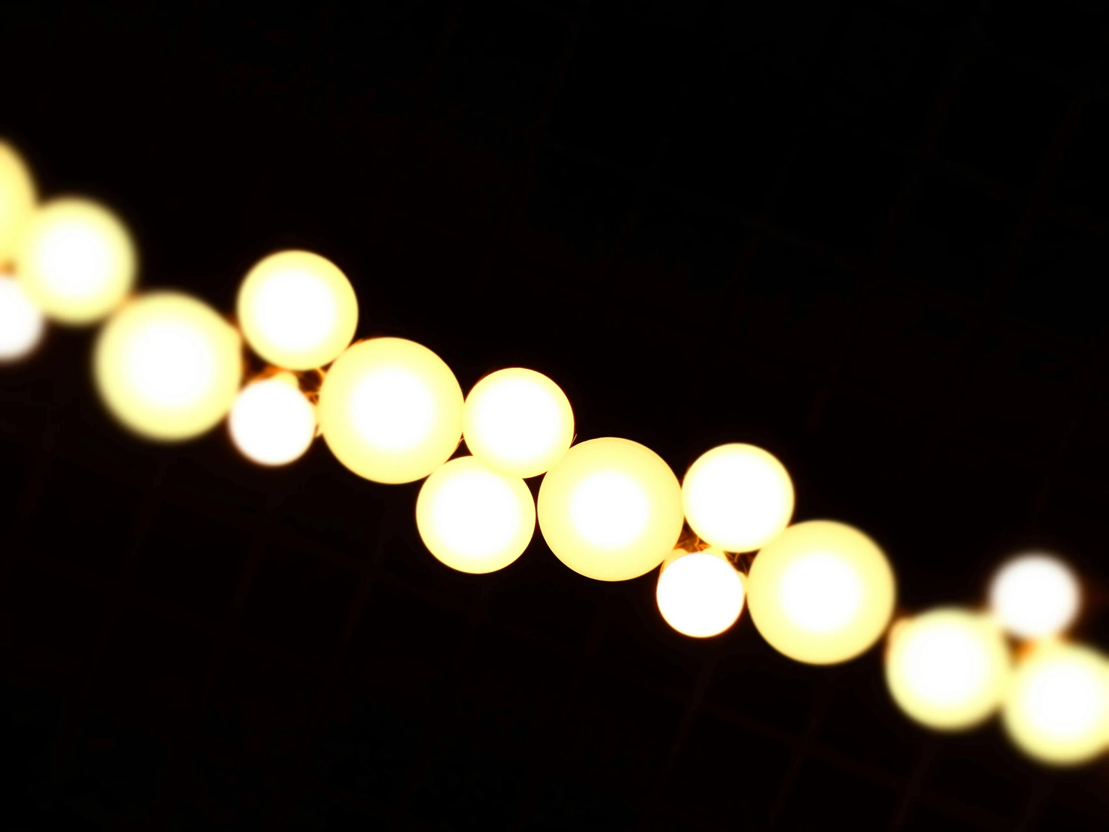 a string of lights is lit up in the dark, a picture, inspired by Bruce Munro, minimalism, soft golden hour lighting, backscatter orbs, cinematic shot ar 9:16 -n 6 -g, vanilla - colored lighting