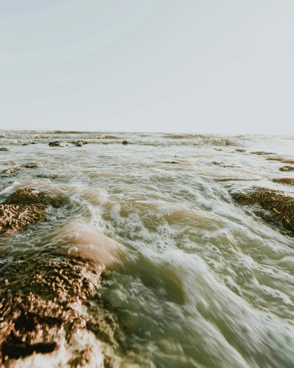 a man riding a surfboard on top of a wave, an album cover, trending on unsplash, happening, erosion channels river, algae, low quality photo, australian beach