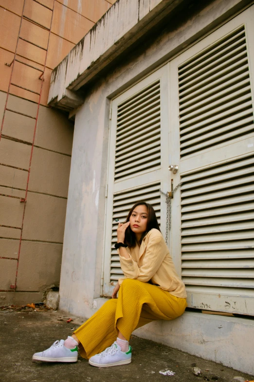 a woman sitting on the side of a building talking on a cell phone, inspired by Ni Yuanlu, trending on pexels, realism, yellow color scheme, leaning on door, ulzzang, !!! colored photography