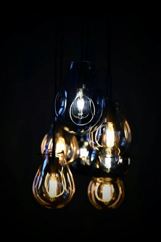a group of light bulbs hanging from a ceiling, rembrandt lighting scheme, with a black background, soft internal light, midnight mist lights