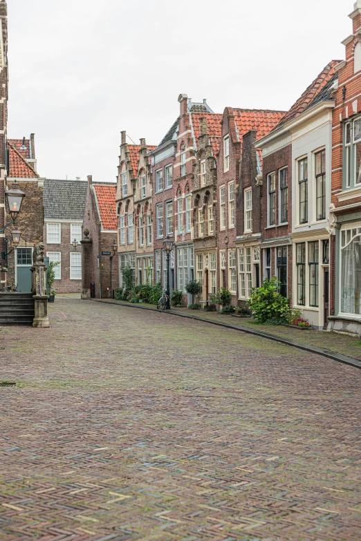 a red fire hydrant sitting on the side of a brick road, by Jan Gregoor, romanesque, houses on stilts, delft, wide view, square