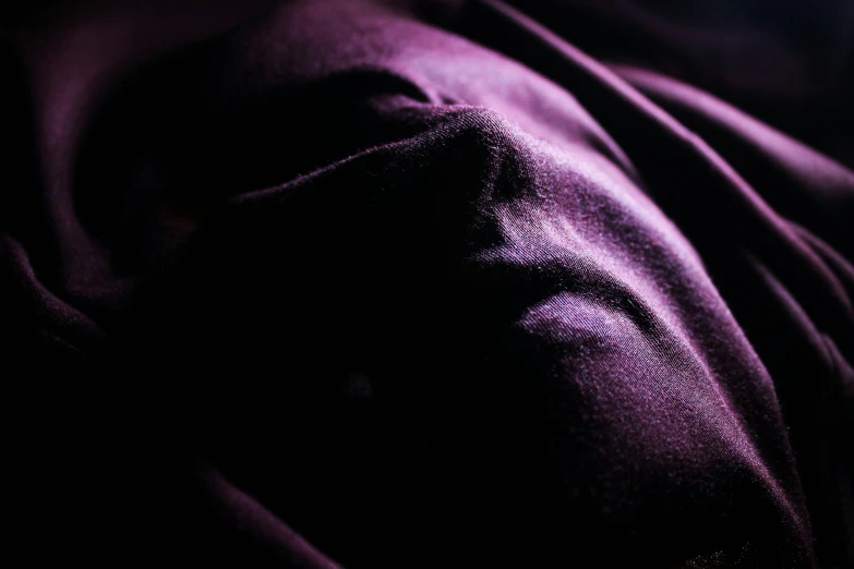 a close up of a person laying on a bed, inspired by Anna Füssli, unsplash, hyperrealism, dark purple garments, with a covered face, purple volumetric lighting, fabric
