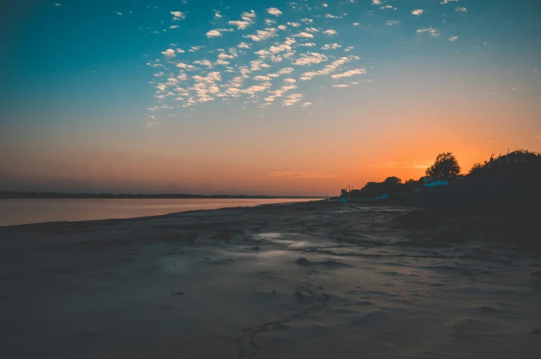 a beach at sunset with footprints in the sand, unsplash contest winner, wide river and lake, assamese aesthetic, skies, high quality image”