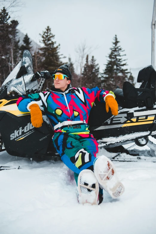 a man sitting in the snow next to a snowmobile, a portrait, inspired by Brian Snøddy, trending on unsplash, pop art, wearing a colorful men's suit, quebec, doing a majestic pose, mittens