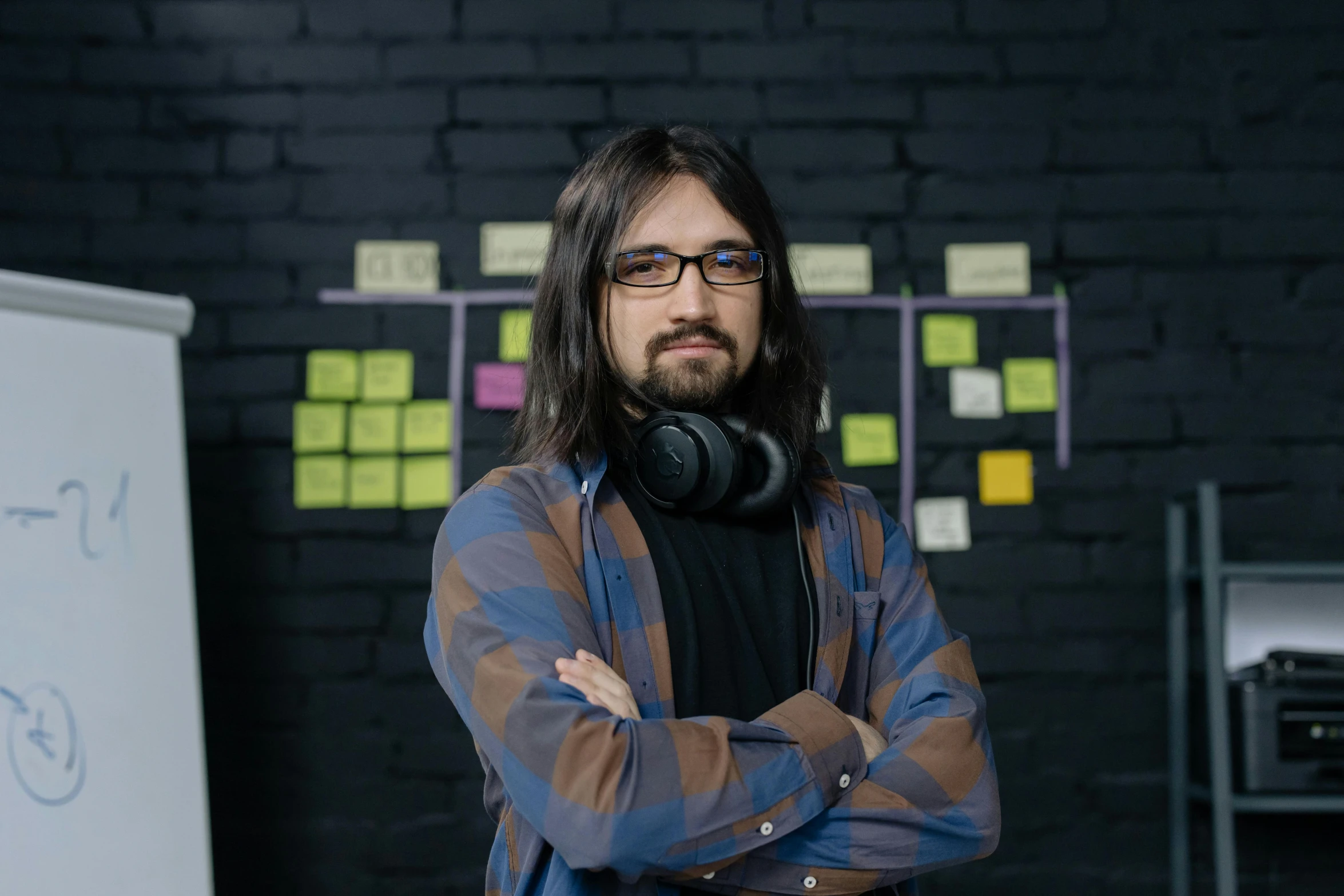 a man wearing headphones standing in front of a whiteboard, pexels contest winner, with his long black hair, hasbulla magomedov, the game designer, against dark background