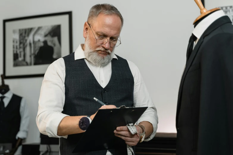 a man standing next to a mannequin holding a clipboard, a photo, academic art, gray beard, signing a bill, wearing a suit and glasses, lgbtq