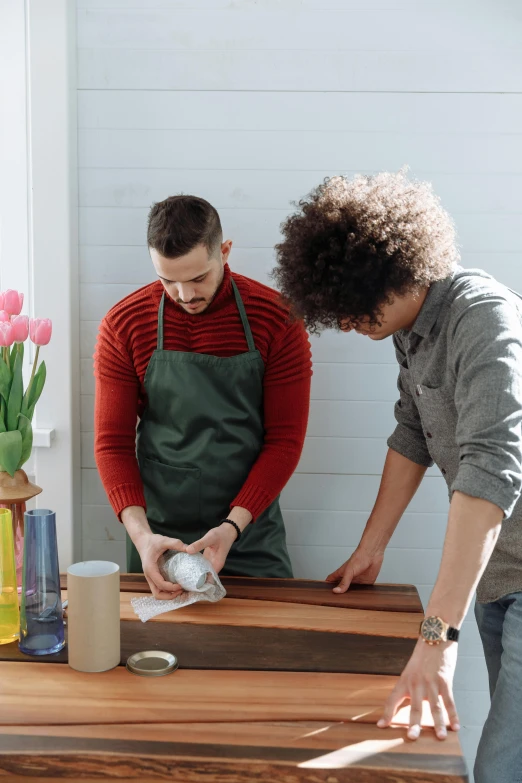 a couple of people that are standing around a table, holding a kitchen knife, on a table, vase work, best practices