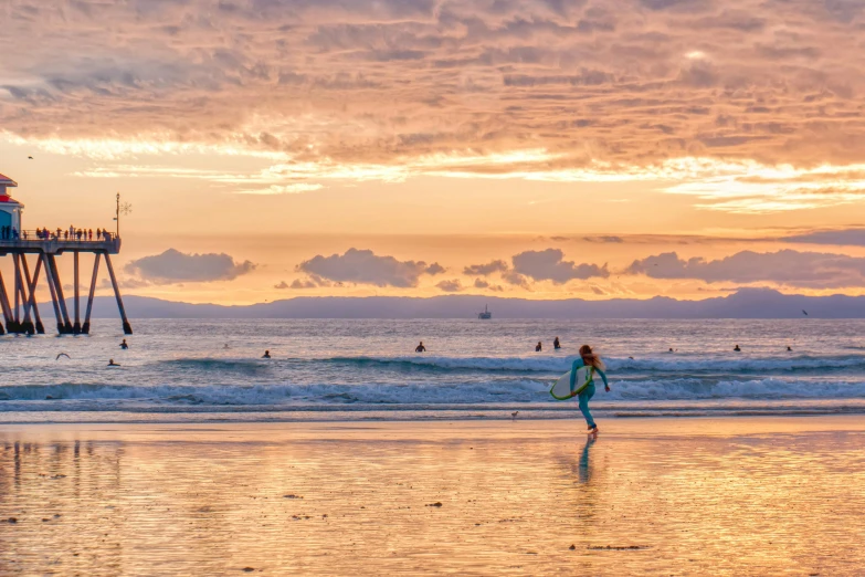 a person walking on a beach with a surfboard, by Charlotte Harding, pexels contest winner, sunset colors, golden bay new zealand, running freely, santa monica beach