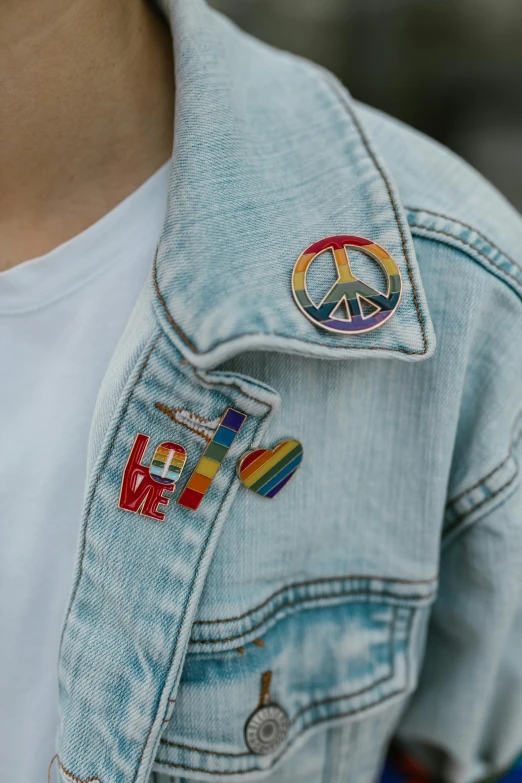 a close up of a person wearing a jean jacket, inspired by Okuda Gensō, trending on pexels, badge, peace and love, band merchandise, set pieces
