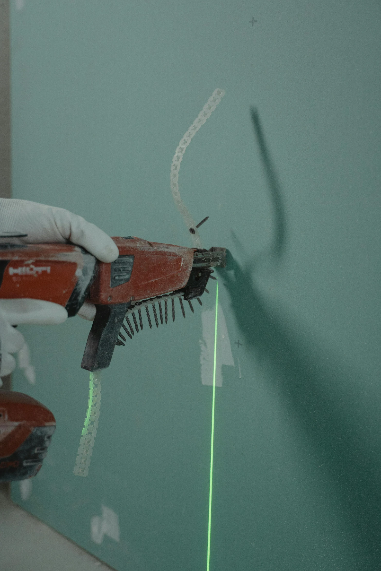 a person using a green light to paint a wall, a hyperrealistic painting, by Ben Zoeller, plasticien, cable wire implants, holding a laser gun, video still, close - up photograph
