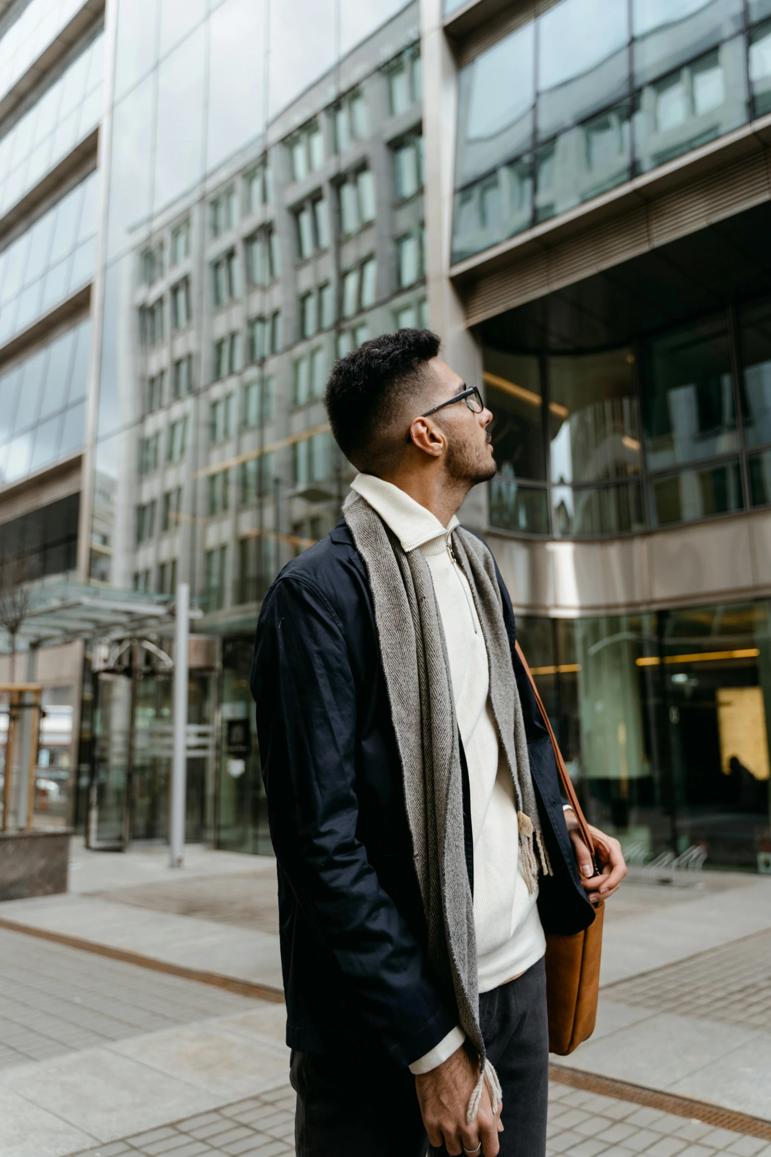 a man standing on a sidewalk in front of a building, trending on pexels, modernism, proud looking away, post graduate, profile pic, diverse