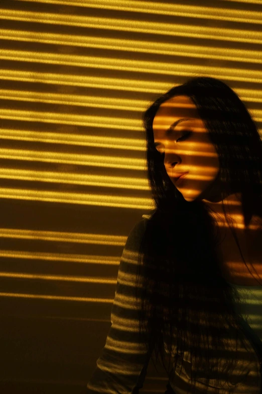a woman standing in front of a yellow light, soft light through blinds, female with long black hair, concerned, light show