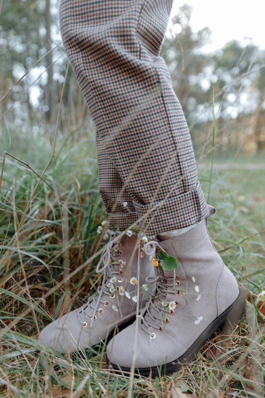 a woman standing on top of a grass covered field, combat boots, tweed colour scheme, next to a plant, outfit photograph