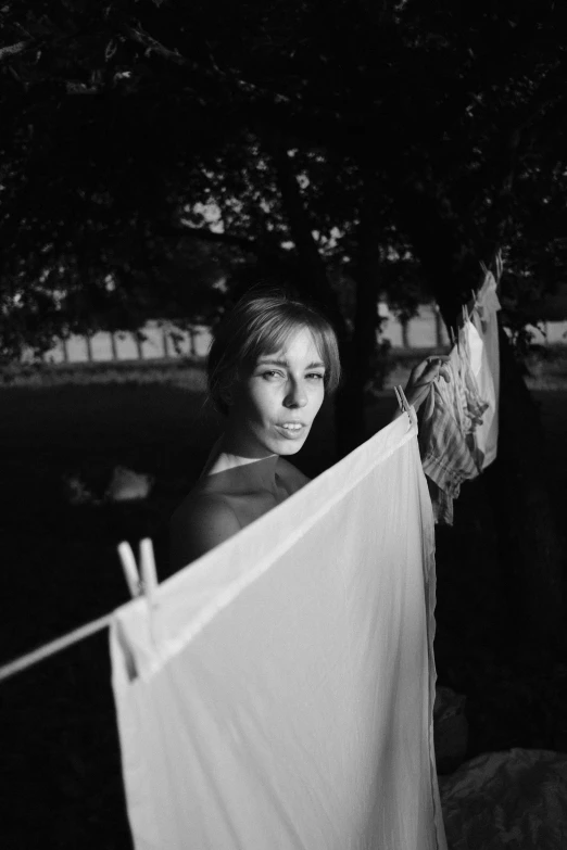 a black and white photo of a woman hanging laundry on a clothes line, by Henri-Julien Dumont, august 1968, portait image, summer evening, loving stare