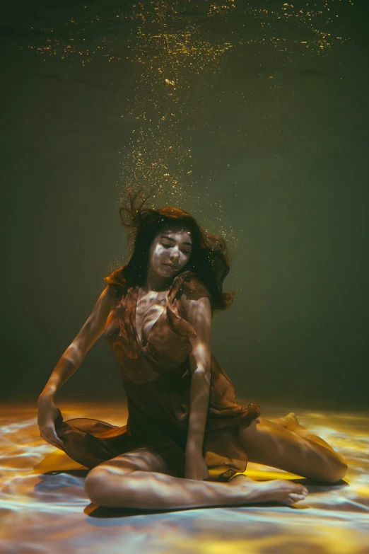 a woman sitting on top of a bed under water, inspired by Brooke Shaden, unsplash contest winner, gold bodypaint, dark yellowish water, underwater face, in a medium full shot