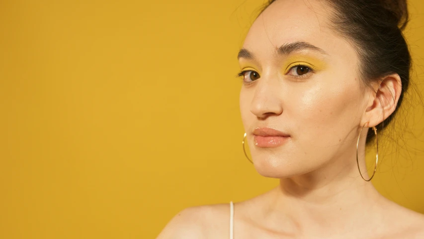 a woman with yellow eyeshadow and gold hoop earrings, inspired by Elsa Bleda, trending on pexels, gemma chen, skincare, portrait sophie mudd, gradient yellow