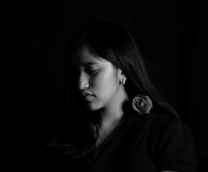 a black and white photo of a woman using a cell phone, a black and white photo, by reyna rochin, pexels contest winner, realism, girl with a flower face, dramatic lowkey studio lighting, indian girl with brown skin, portrait of depressed teen