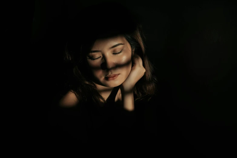 a woman with her eyes closed in the dark, a picture, light and shadow, a young asian woman, portrait image, instagram post