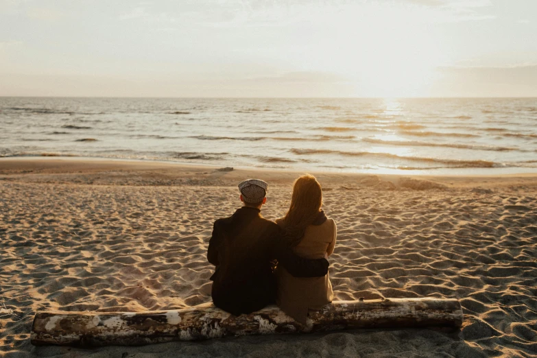 a couple of people sitting on top of a sandy beach, pexels contest winner, soft warm light, profile image, 1792